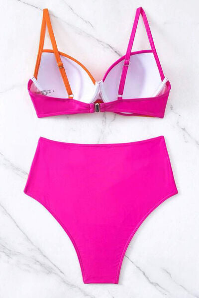 The back view of a vibrant pink and orange contrast sweetheart neck bikini set with a two-piece design, high-waisted bottom, and removable padding, laying on a marble background.