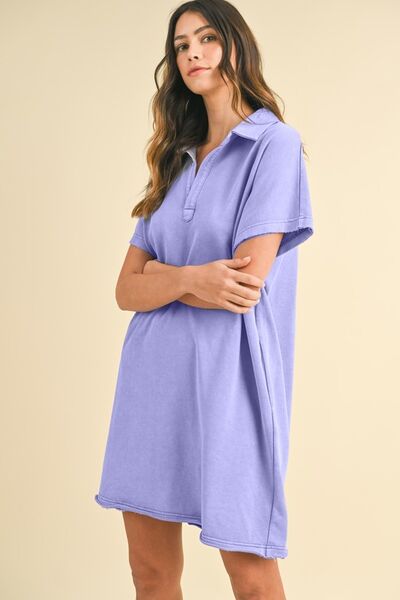 A woman wearing a blue purple mineral-washed Johnny collar short sleeve dress with a relaxed fit and pockets, styled for a casual and effortless look. 